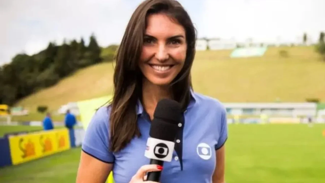 Glenda Kozlowski com microfone da TV Globo durante cobertura esportiva em campo de futebol