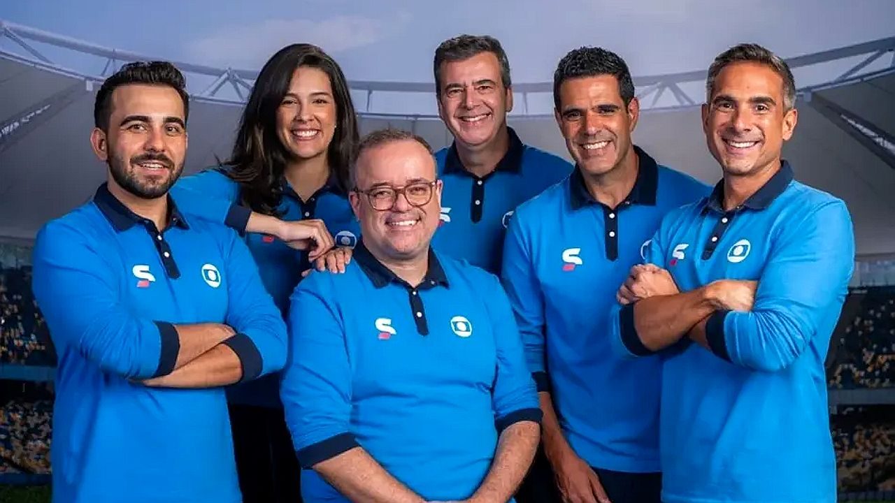 Equipe de esportes da Globo reunida em foto promocional da cobertura da Copa do Mundo em estádio ao fundo