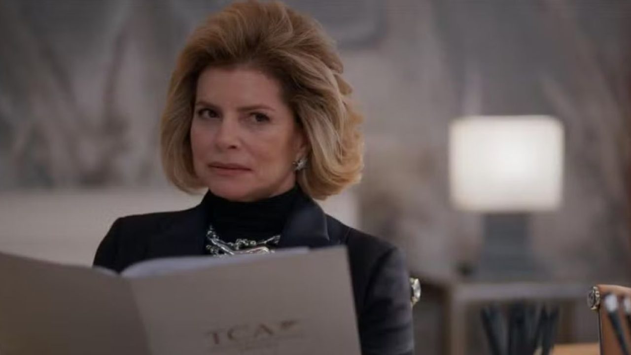 Na imagem, a personagem Odete Roitman aparece em cena do remake da novela Vale Tudo (2025), exibindo um olhar desconfiado e expressão firme. Sentada em um ambiente elegante e moderno, ela segura uma pasta com a sigla "TCA", sinalizando um momento de reunião ou decisão empresarial.