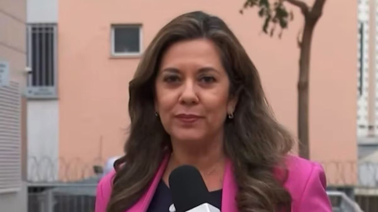 Graciela Andrade faz entrada ao vivo com microfone durante cobertura jornalística em frente a condomínio
