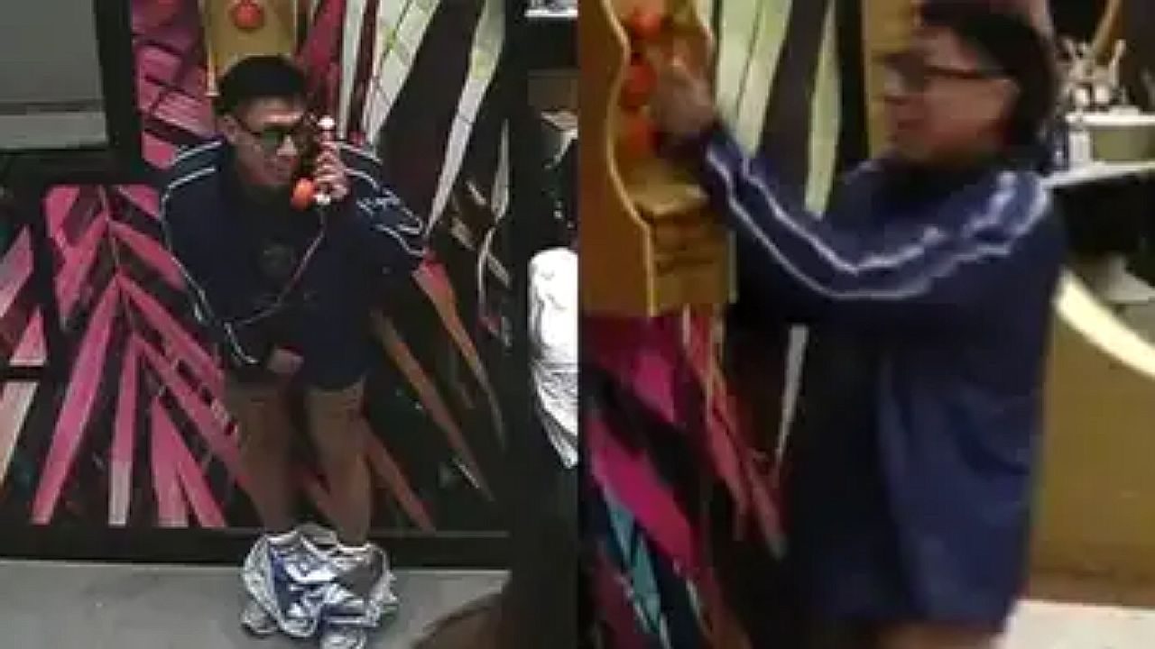 Homem usa telefone fixo em cabine colorida enquanto aparece em duas cenas simultâneas de reality show em ambiente interno