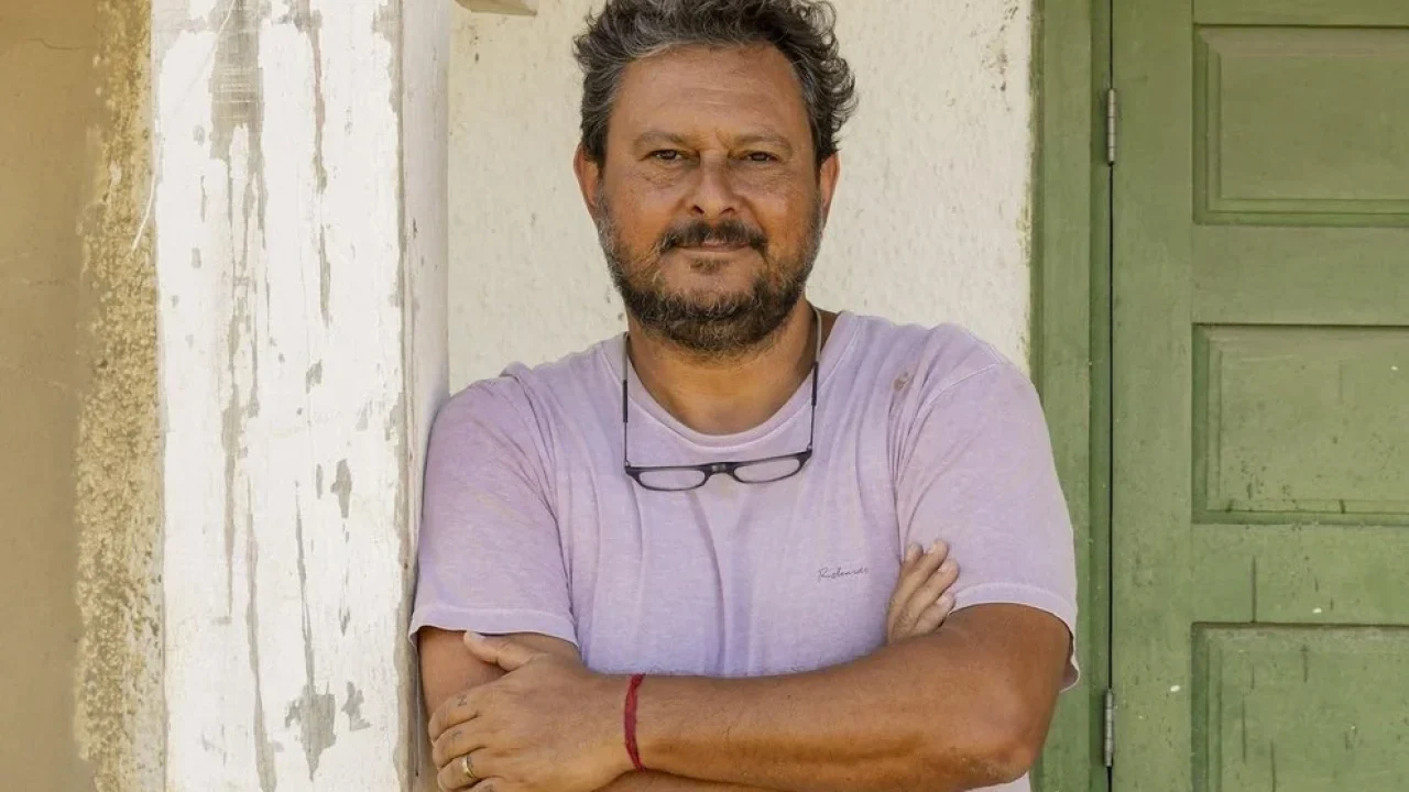 Diretor de Pantanal, da Globo, Gustavo Fernandez com os braços cruzados encostado em parede externa durante bastidores de novela