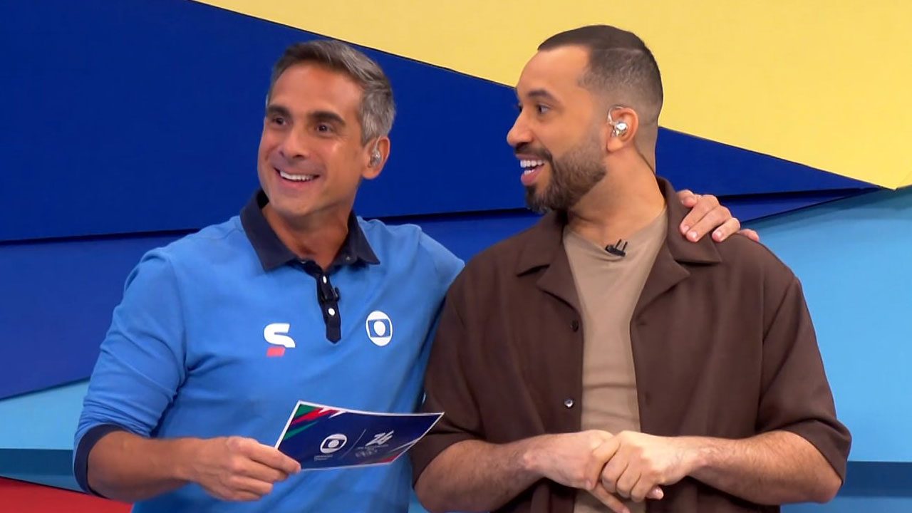 Gustavo Villani e Gil do Vigor sorriem abraçados em estúdio da Globo durante transmissão dos Jogos Olímpicos de Inverno