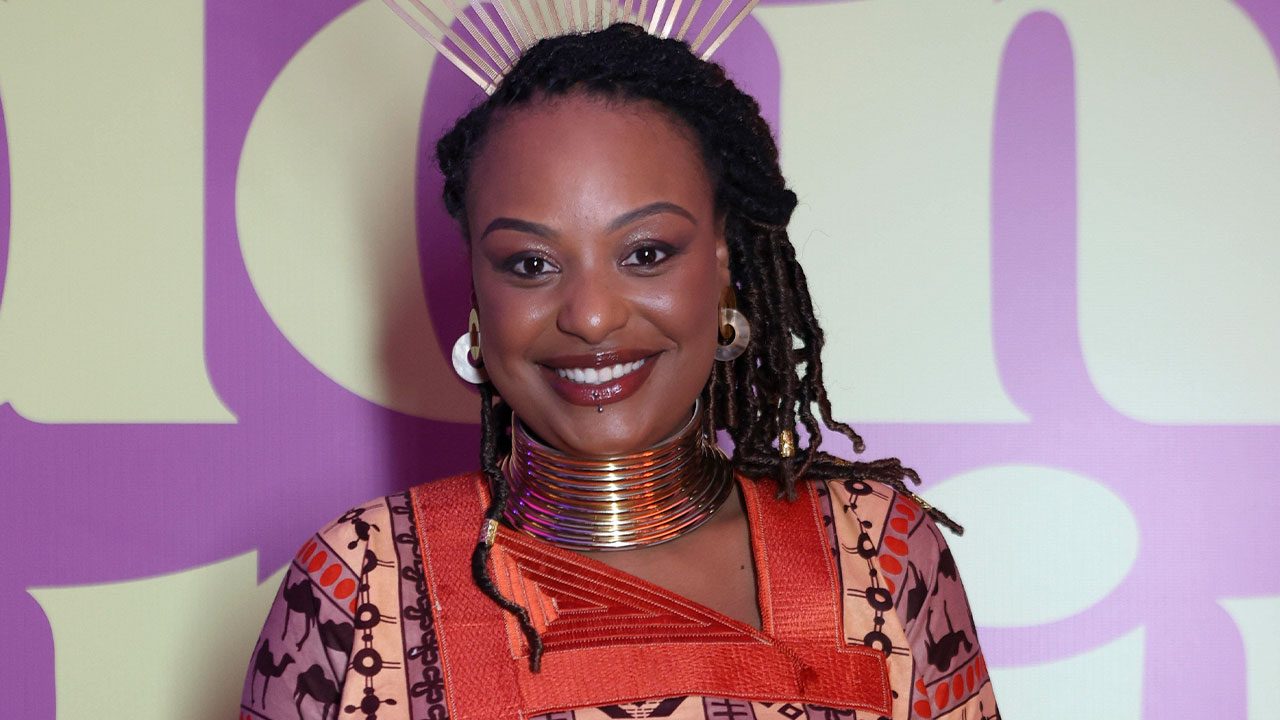 Haonê Thinar sorrindo no lançamento de Dona de Mim com look estampado e colares metálicos largos