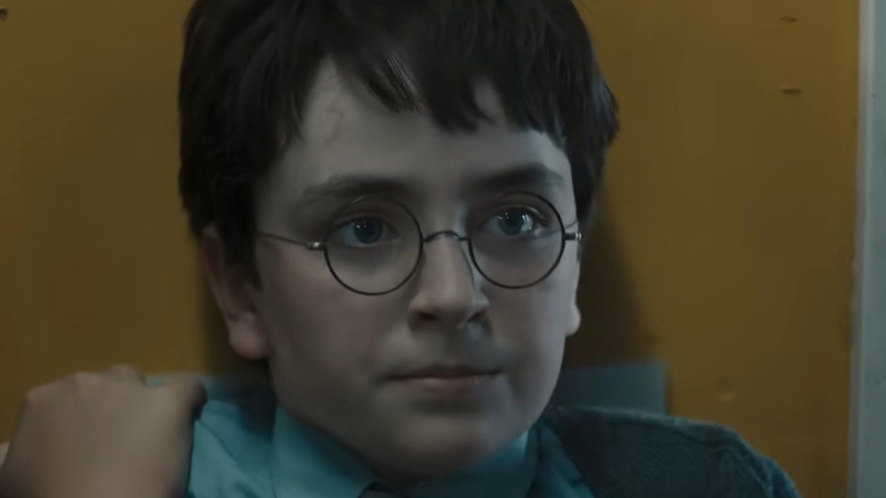 Dominic McLaughlin como Harry Potter aparece de óculos redondos com expressão séria em ambiente interno com parede amarela ao fundo