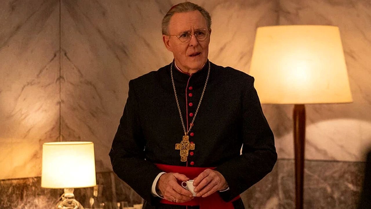 Cardeal com vestes religiosas e cruz dourada segura xícara em sala com iluminação suave e decoração clássica