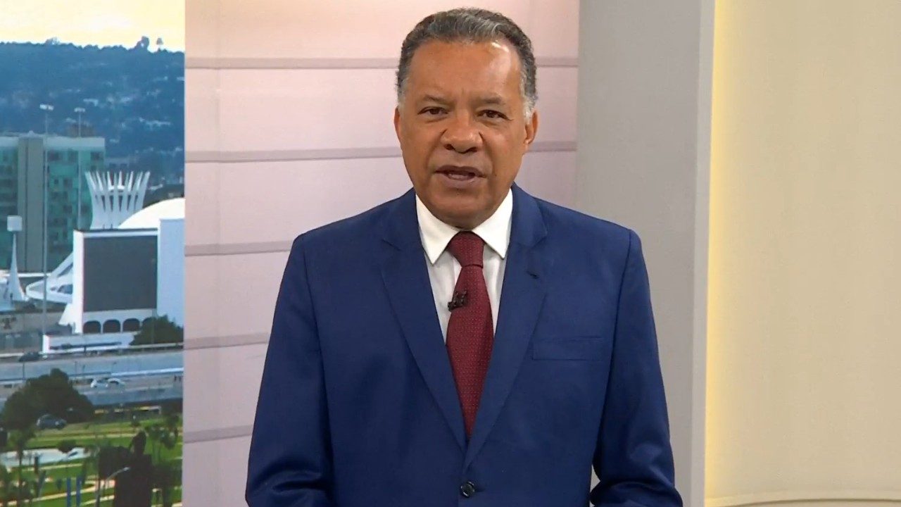 Heraldo Pereira usa terno azul e gravata vermelha durante apresentação do Bom Dia Brasil com Brasília ao fundo