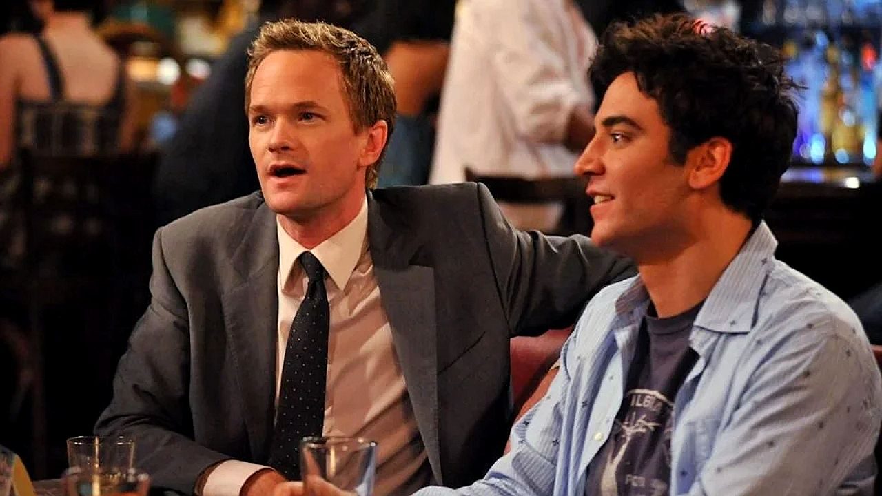 Dois amigos conversam em bar enquanto bebem cerveja em cena da série How I Met Your Mother