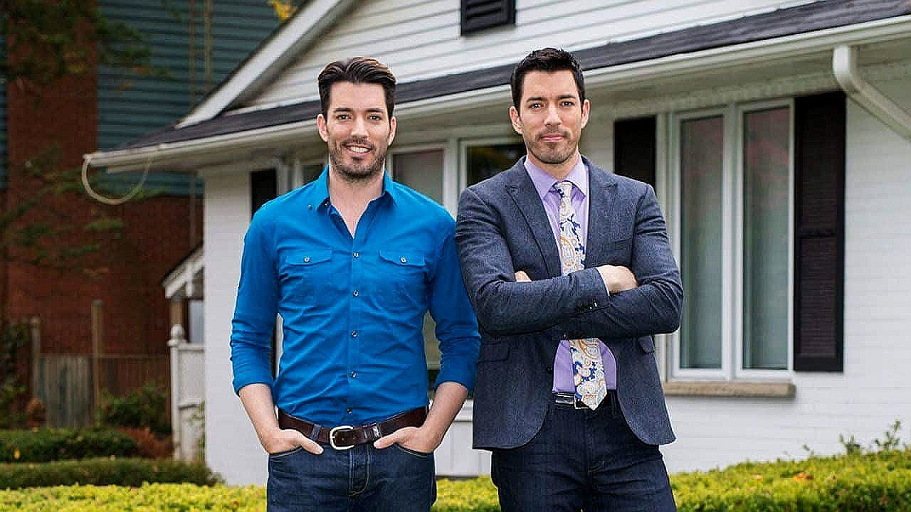 Jonathan e Drew Scott posam em frente a uma casa em foto promocional do programa Irmãos à Obra