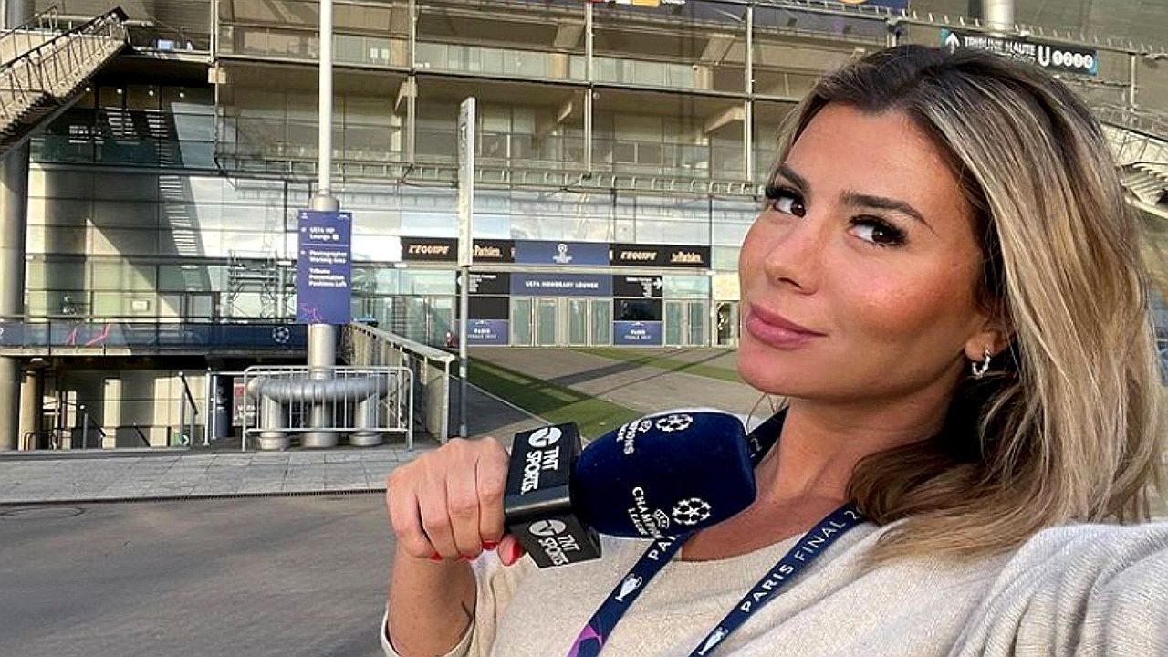 Repórter esportiva segura microfone da TNT Sports em frente a estádio durante cobertura da Champions League