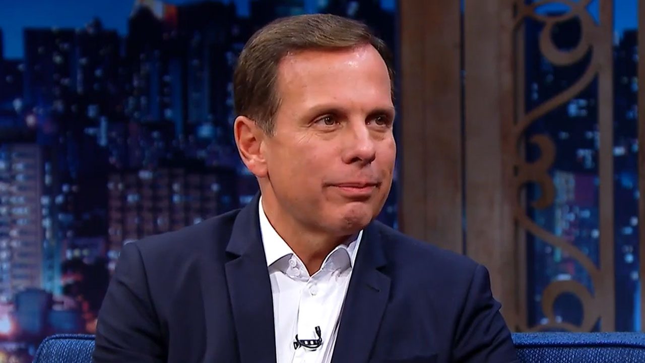 João Doria sentado no sofá do The Noite durante entrevista no cenário do talk show