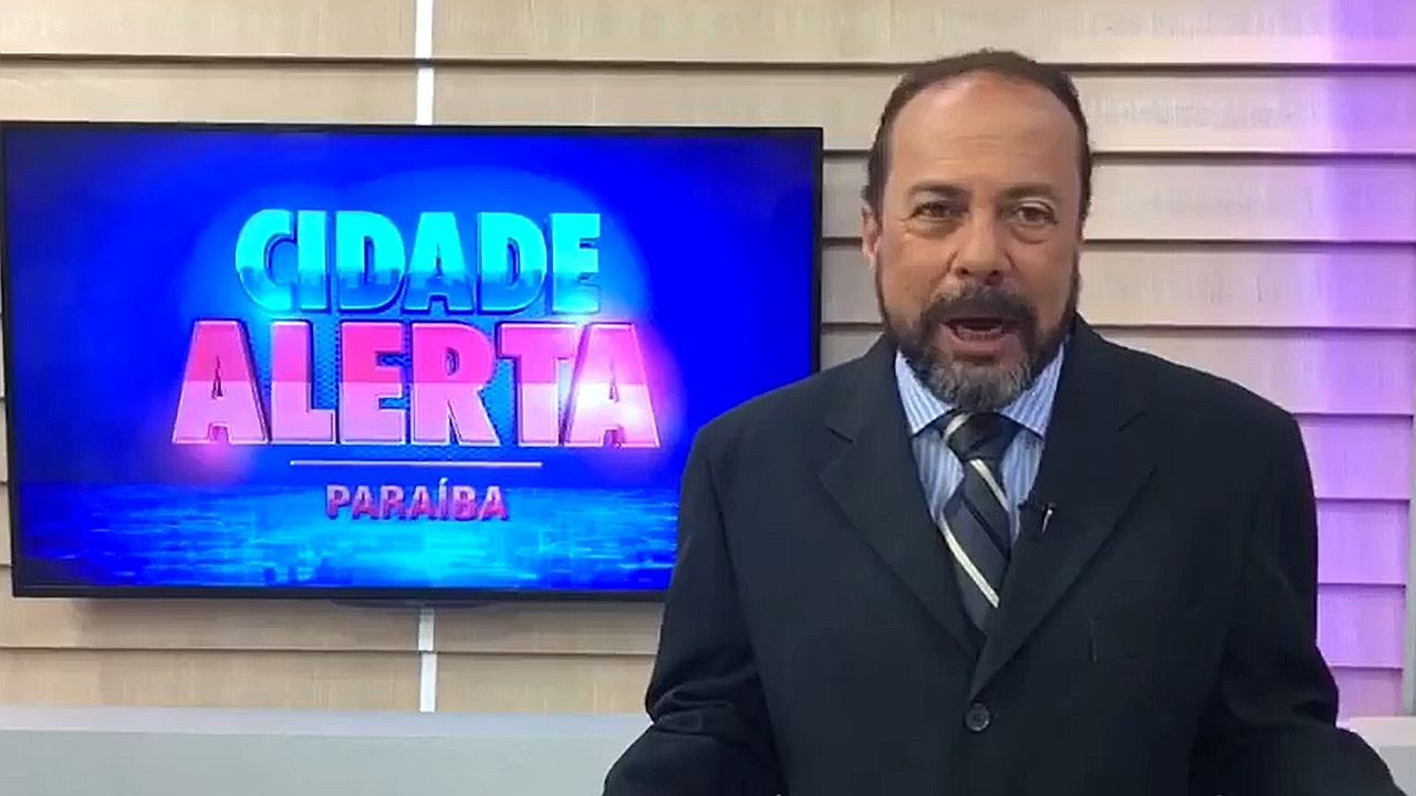 Apresentador fala no estúdio do Cidade Alerta Paraíba com telão do programa ao fundo