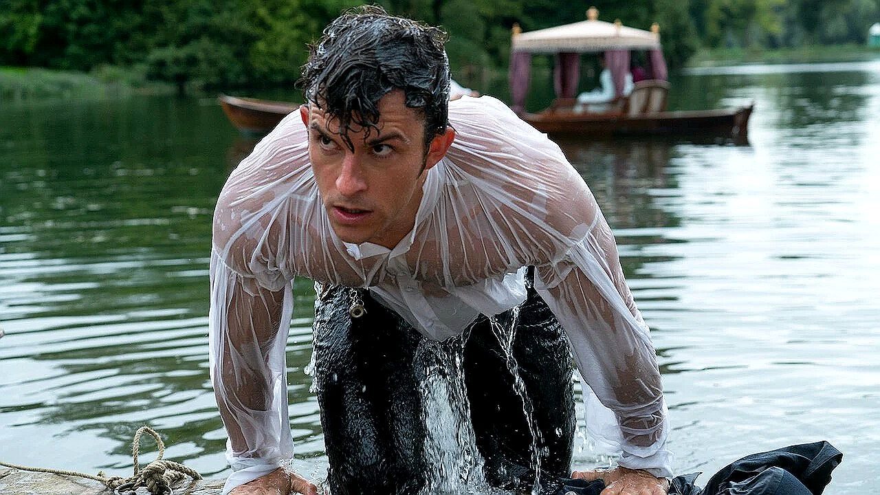 Jonathan Bailey emerge encharcado de lago com camisa branca molhada em cena de série