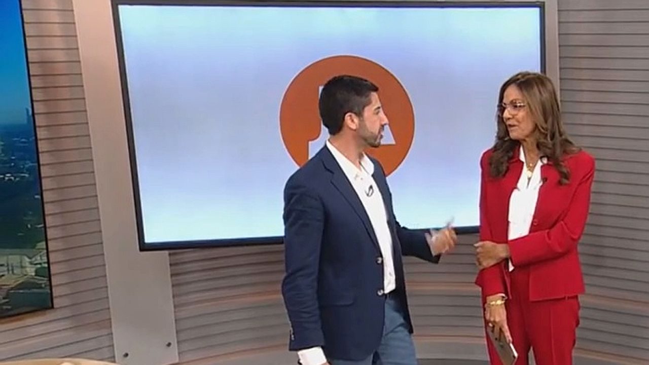 Apresentadores conversam no estúdio do Jornal do Almoço diante de telão com a identidade visual do telejornal