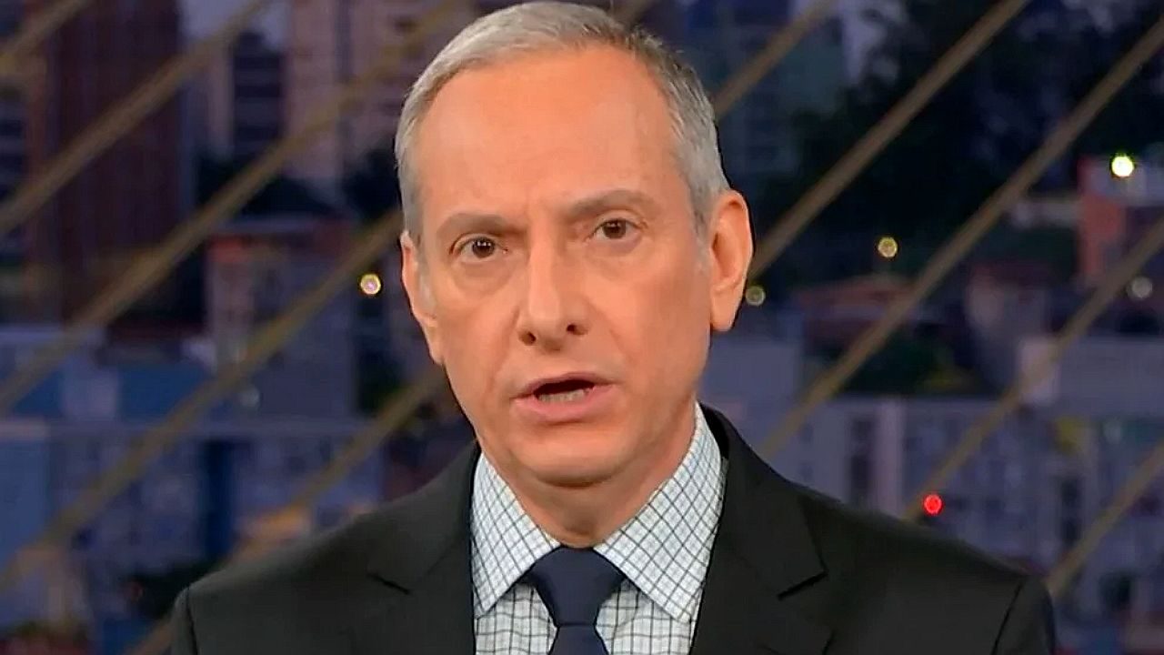 Jose Roberto Burnier em um terno com um estúdio escuro no fundo