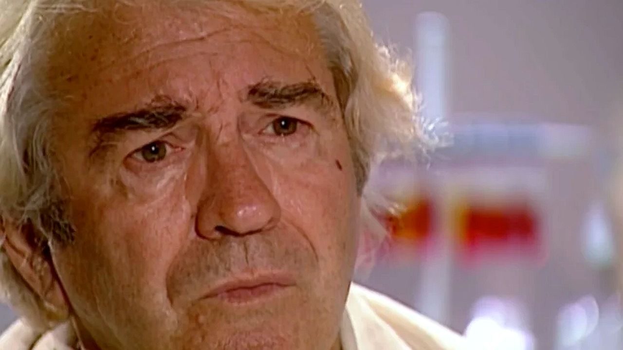 Homem idoso de cabelos grisalhos aparece em close com expressão séria durante entrevista em ambiente interno