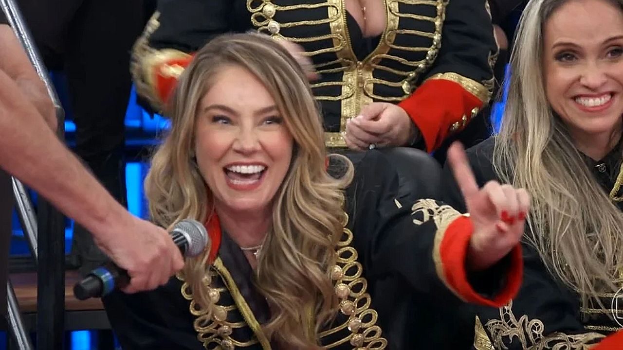 Juliana Baroni sorri e aponta para a plateia durante participação em programa de auditório na televisão