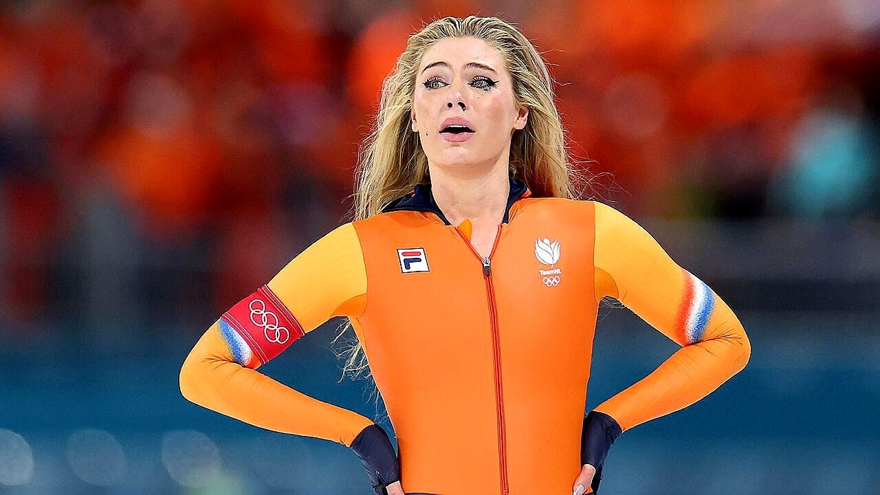 Mulher atleta de patinação de velocidade usa uniforme laranja da Holanda com símbolo olímpico em competição no gelo