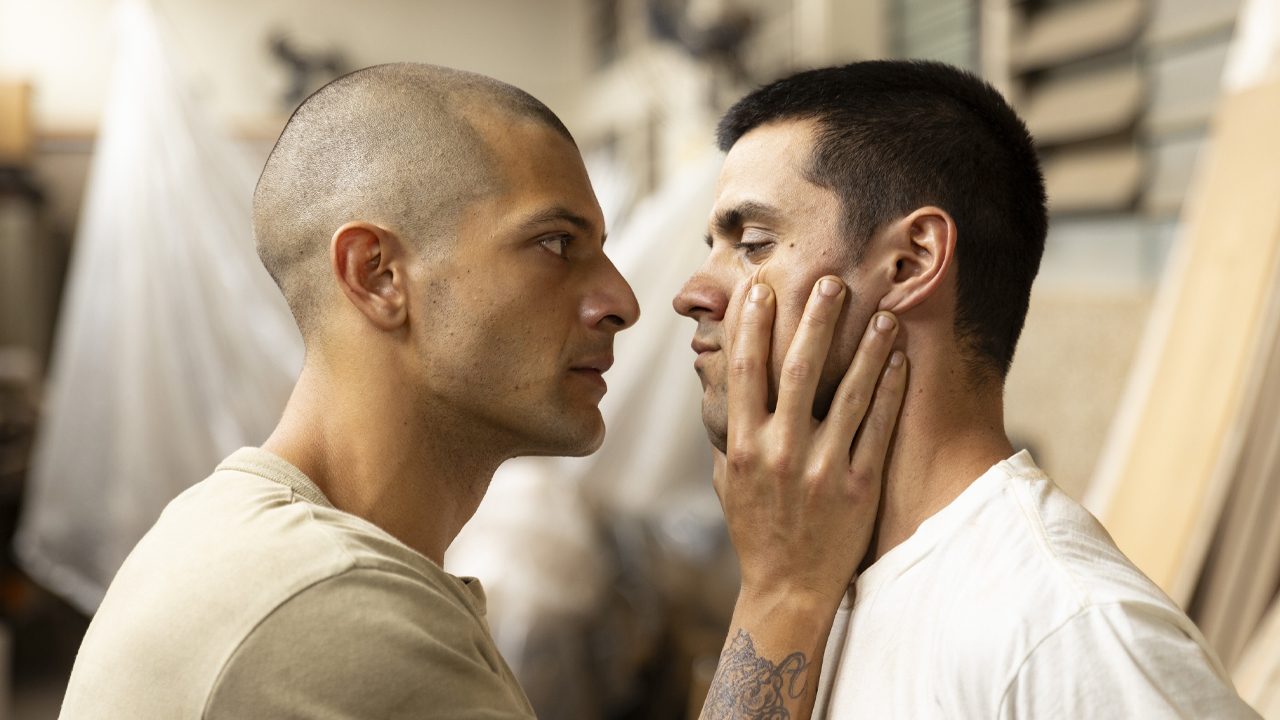 Kelner Macêdo e Felipe Simas de perfil, um olhando para o outro, em cena da série dramática brasileira Tremembé