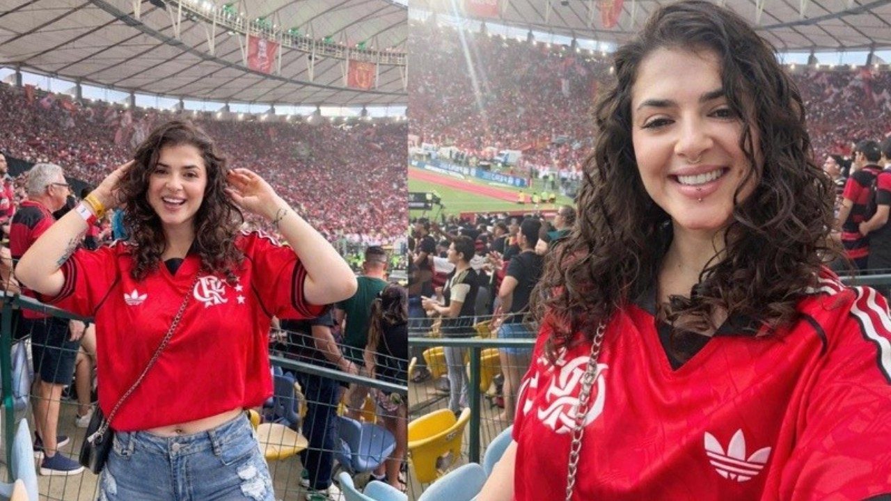 Kerolay Chaves sorri usando camisa vermelha do Flamengo e short jeans, cabelos cacheados soltos, em arquibancada lotada do Estádio do Maracanã ao fundo