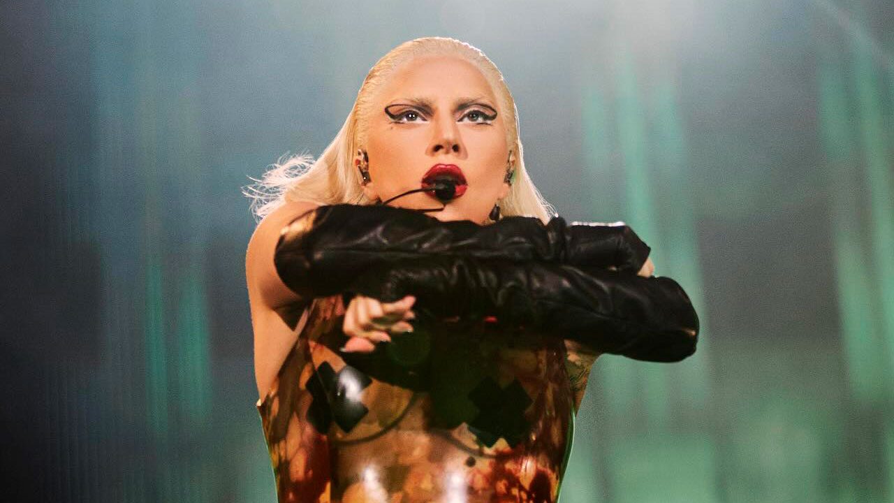 Lady Gaga com figurino ousado e maquiagem marcante durante apresentação com microfone de cabeça
