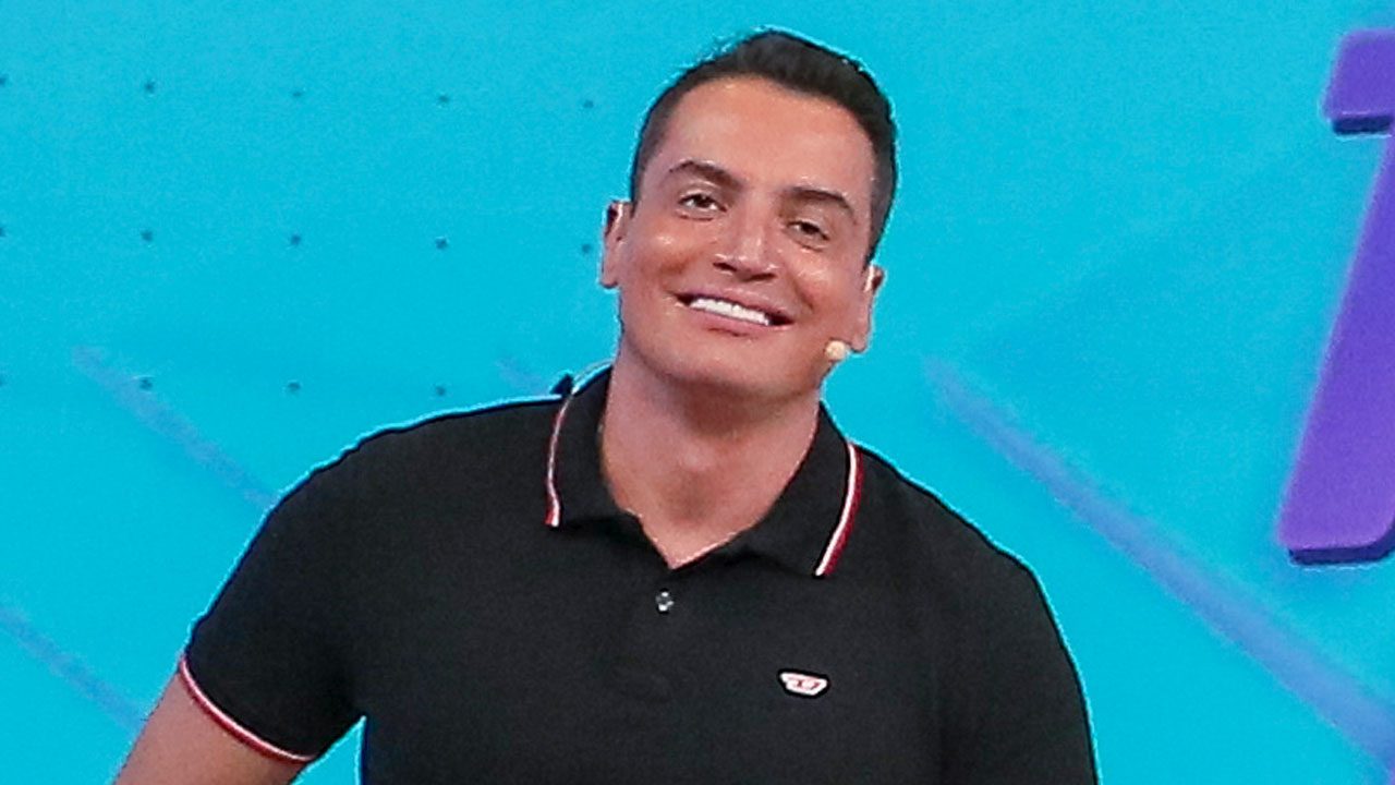 Leo Dias sorrindo no estúdio do Fofocalizando com microfone preso ao rosto