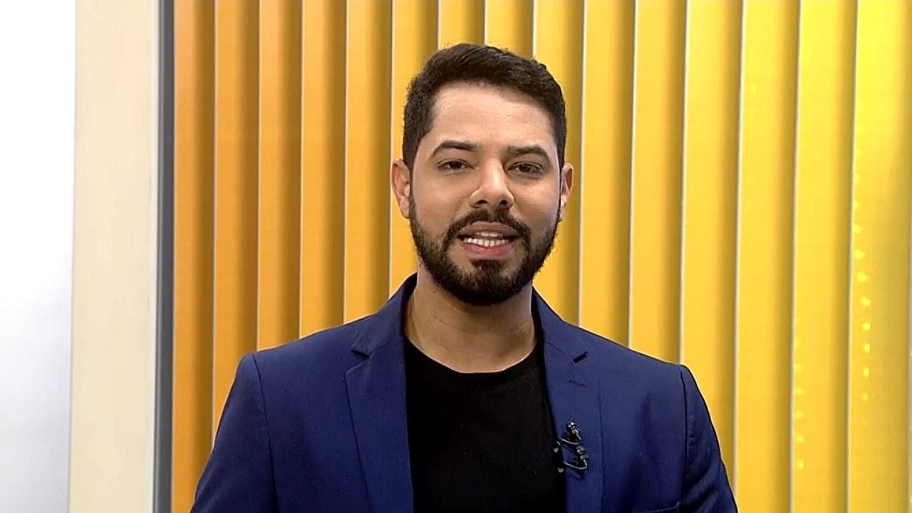 Apresentador fala durante programa de TV em estúdio com painel amarelo ao fundo