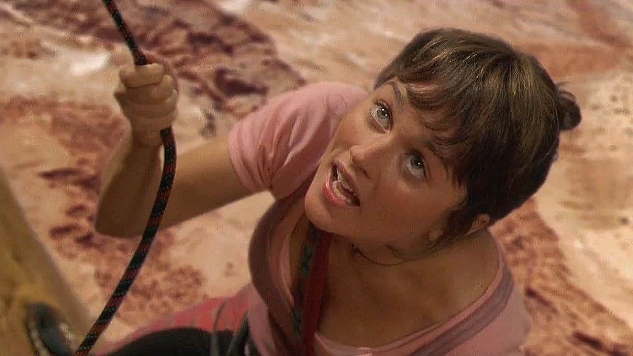 Annie Garrett escala paredão de rocha com corda em cena do filme Limite Vertical