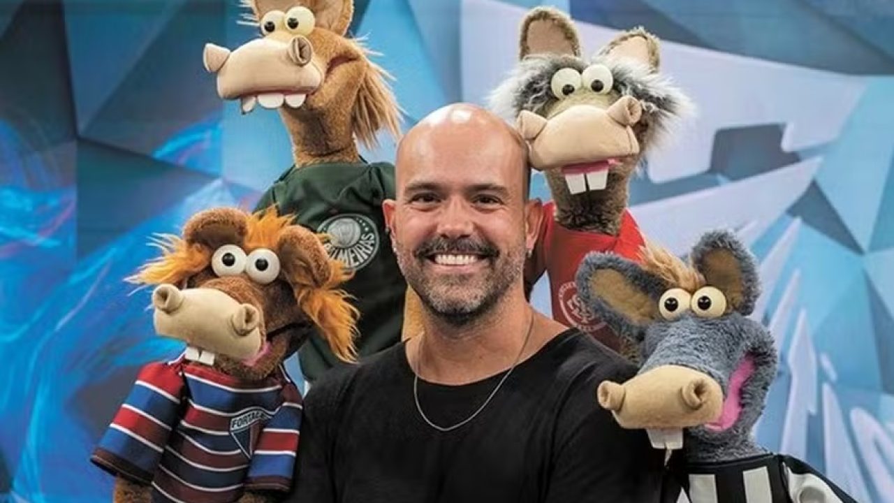 A imagem mostra o jornalista Lucas Gutierrez ao lado dos famosos Cavalinhos do Fantástico, marcando sua nova fase como apresentador do quadro no dominical da TV Globo. Ele aparece sorridente, vestindo uma camiseta preta e um colar prateado, demonstrando entusiasmo com o desafio.