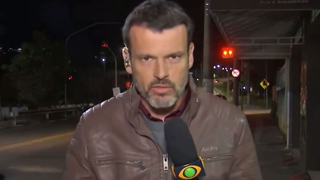 Lucas Martins segura microfone da Band durante entrada ao vivo em rua à noite