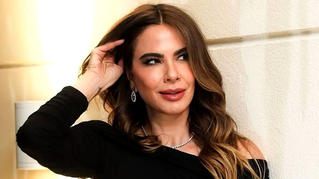 Luciana Gimenez com vestido preto e cabelo ondulado durante evento posa olhando para o lado