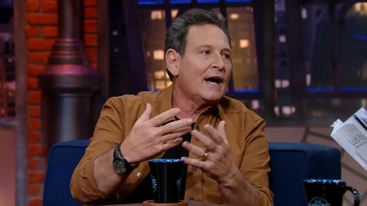 Luis Ricardo com uma jaqueta marrom e uma blusa preta