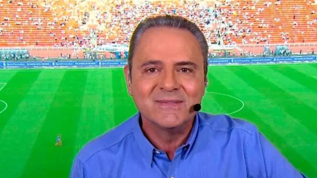 Luis Roberto sorri com headset de transmissão diante do gramado durante cobertura de partida de futebol
