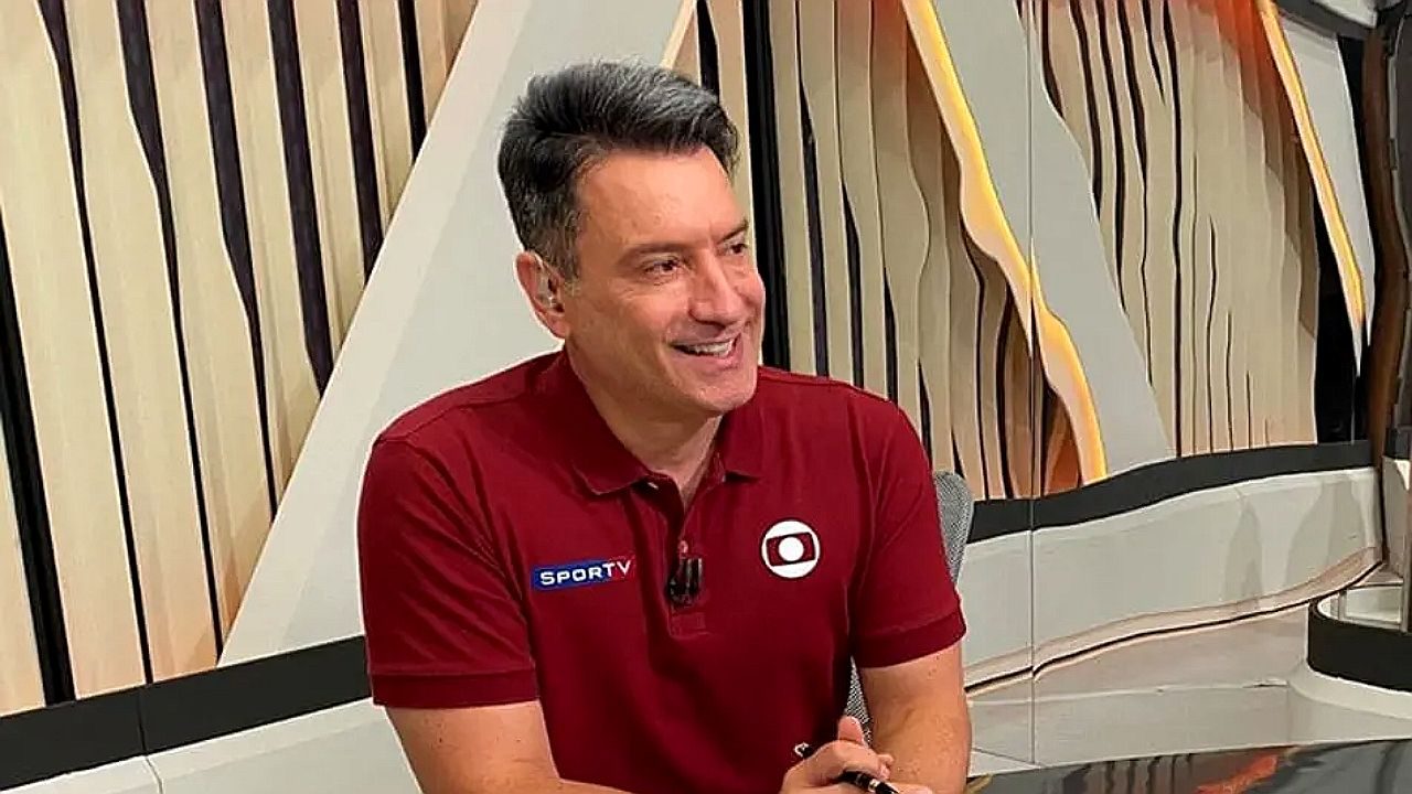 Luiz Carlos Jr. sorri durante transmissão esportiva da Globo usando camisa vermelha do sportv no estúdio