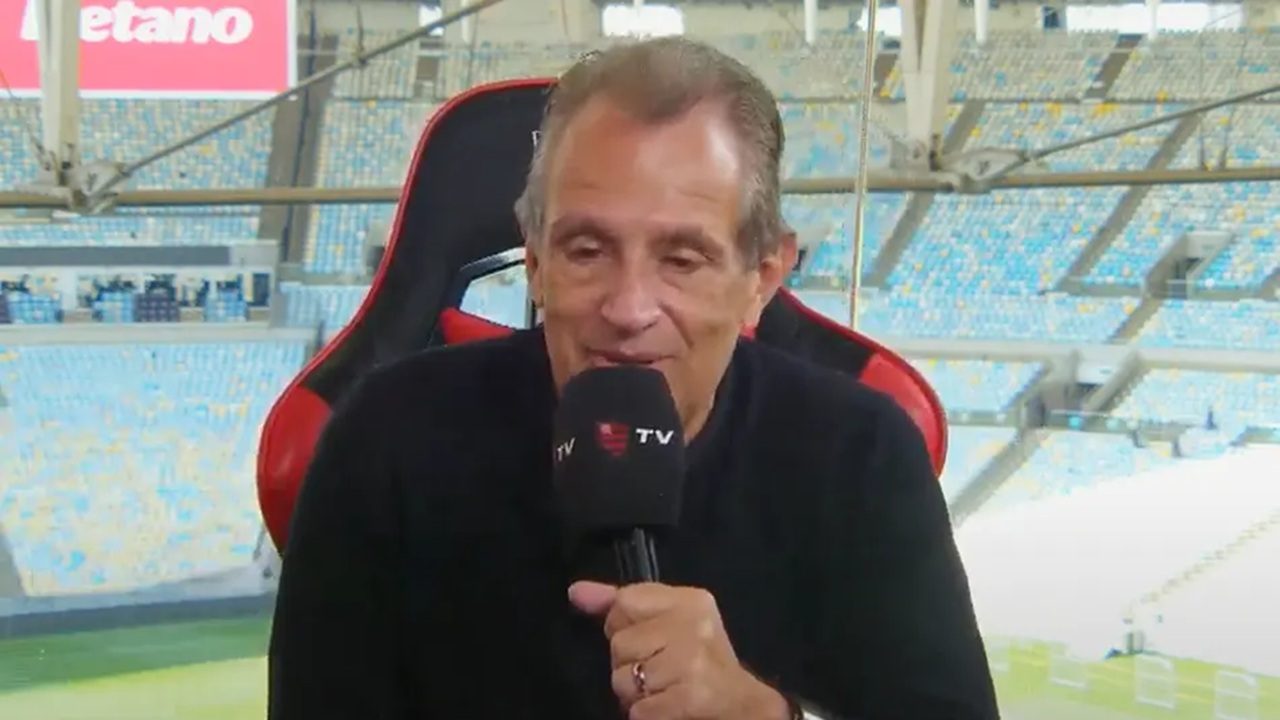 Homem com microfone da FlaTV fala em transmissão esportiva no estádio do Maracanã com arquibancadas ao fundo