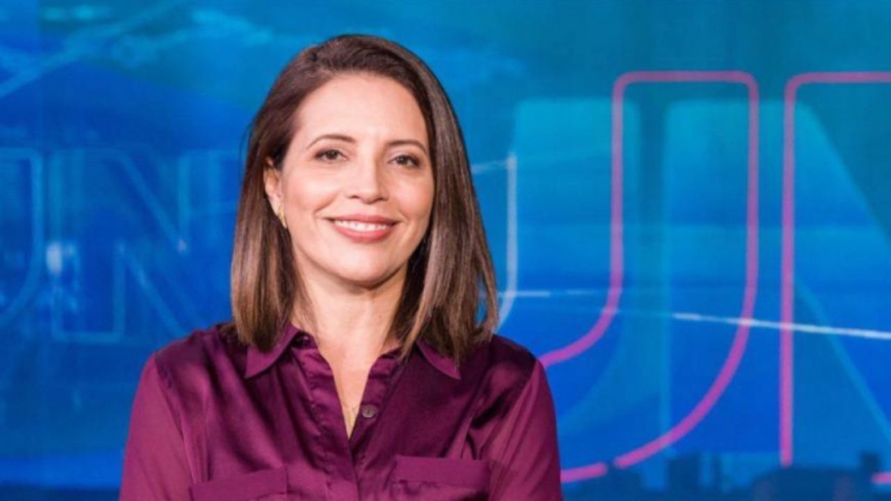 Luzimar Collares sorrindo no estúdio do Jornal Nacional com o telão azul da Globo ao fundo