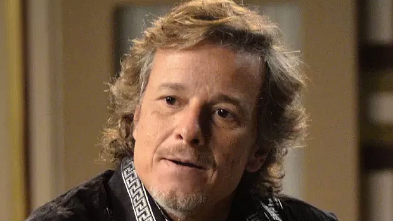 Marcello Novaes em cena de novela durante conversa com expressão séria dentro de casa