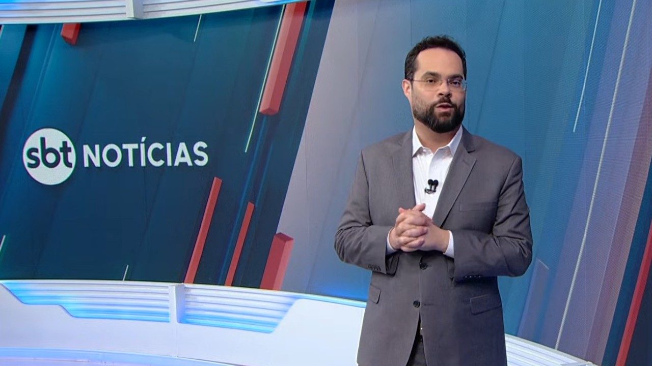 Marcelo Casagrande apresenta o SBT Notícias em estúdio com logotipo do telejornal exibido ao fundo