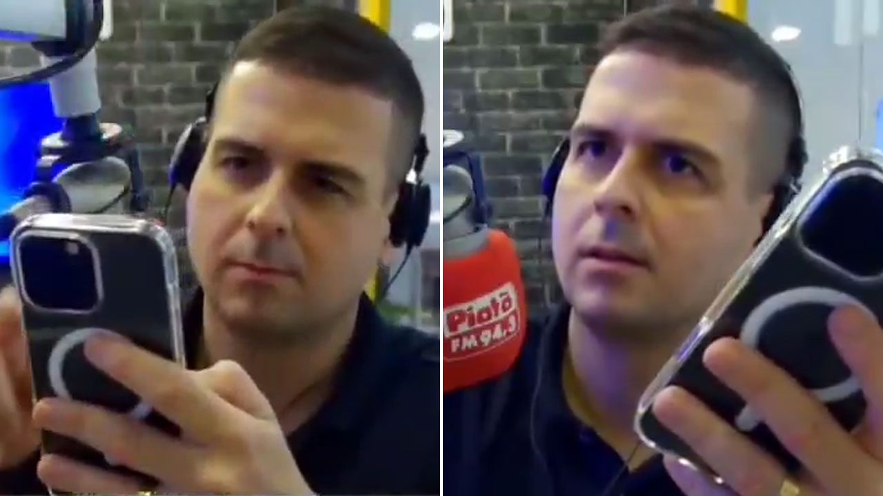 Marcelo Castro usando fones e segurando celular durante transmissão na rádio Piatã FM