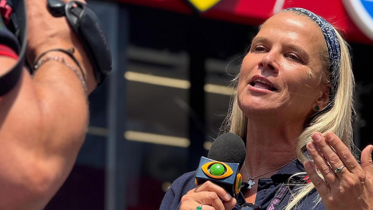 Mariana Becker com microfone da Band falando diante de câmera durante cobertura da Fórmula 1