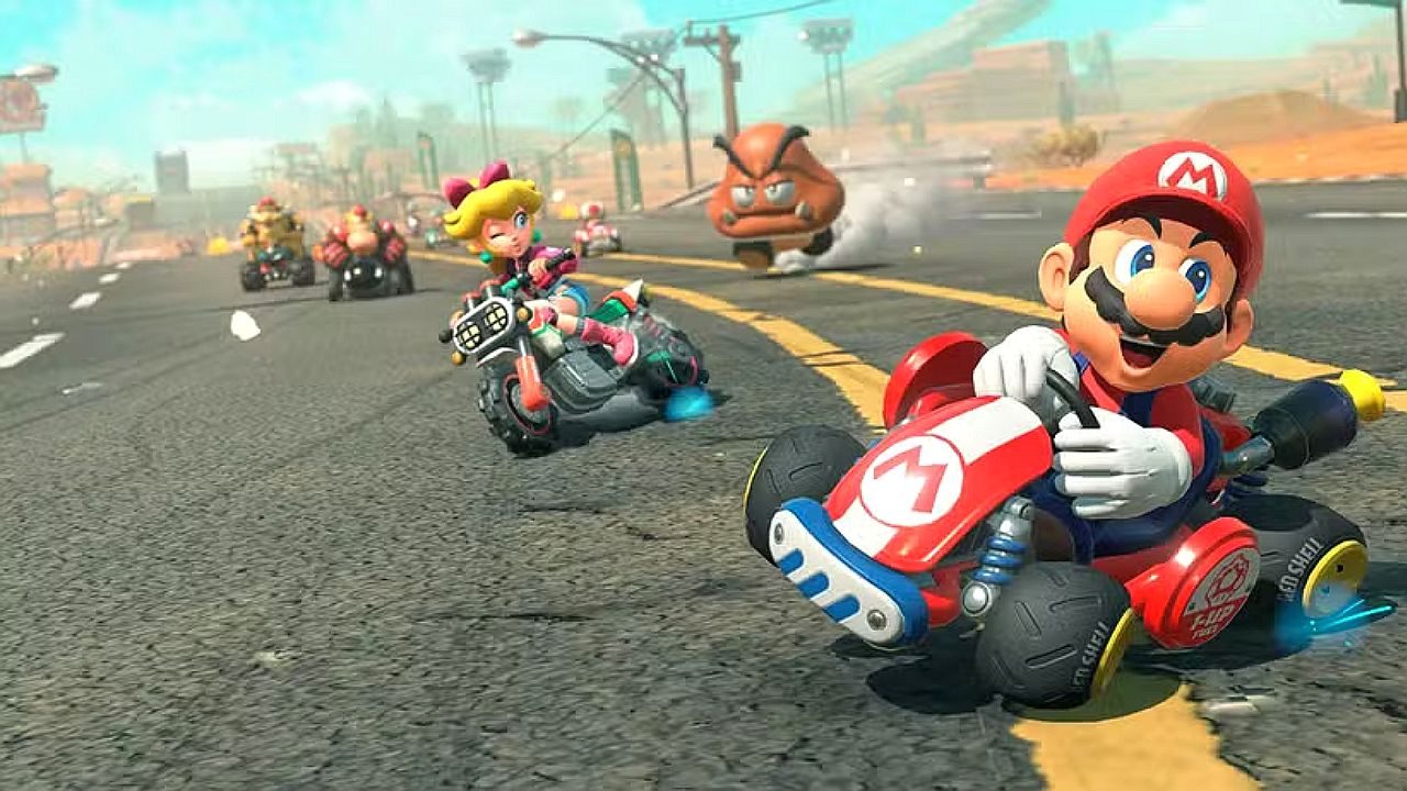 Mario dirige kart vermelho enquanto Peach pilota moto em corrida do jogo Mario Kart na estrada desértica
