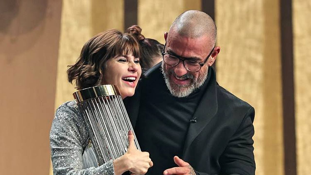 Julianne Trevisol abraça troféu ao lado de chef durante prova do MasterChef em estúdio de televisão