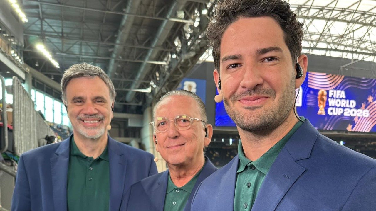 Mauro Beting, Galvão Bueno e Alexandre Pato posam juntos em estádio com telão da Copa do Mundo ao fundo