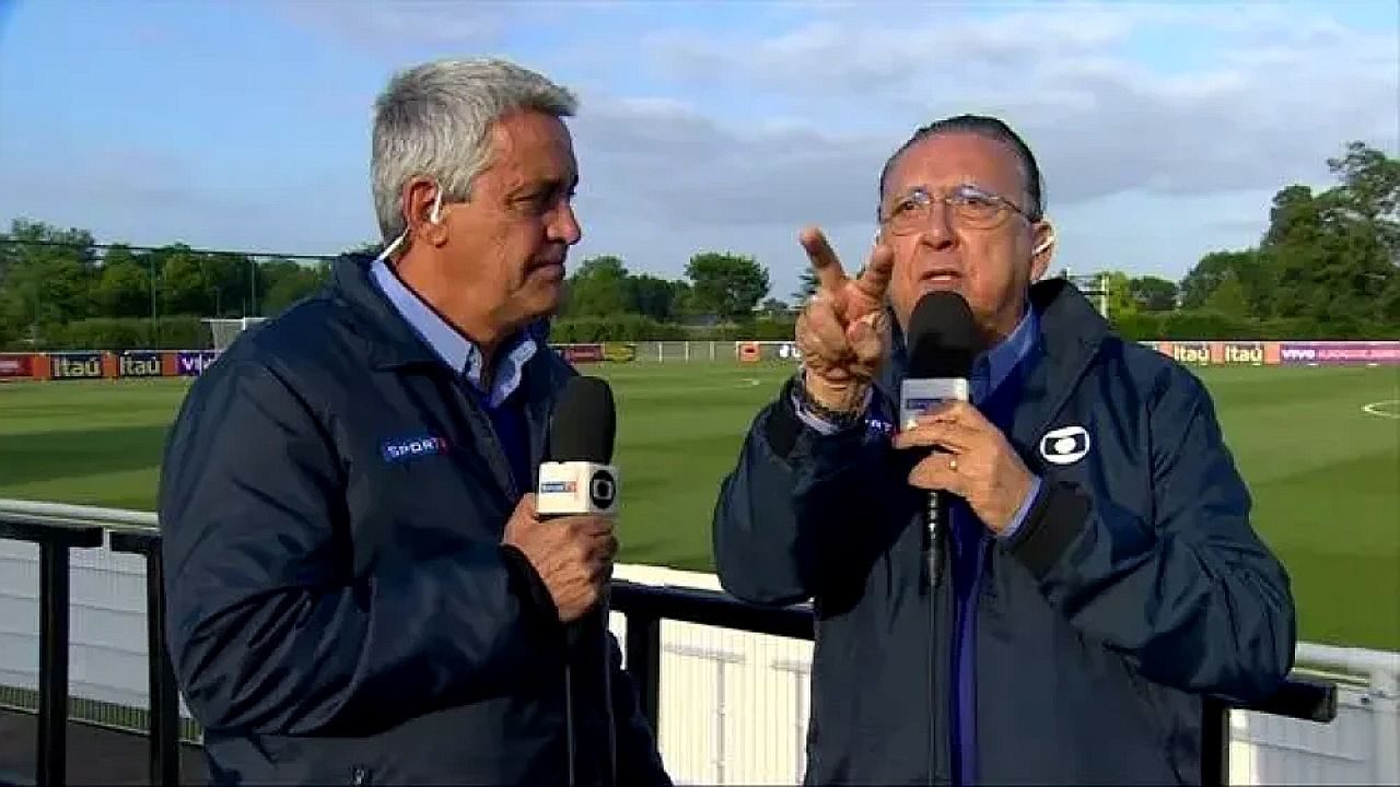 Mauro Naves e Galvão Bueno comentam futebol diante de campo de treinamento durante transmissão esportiva da Globo