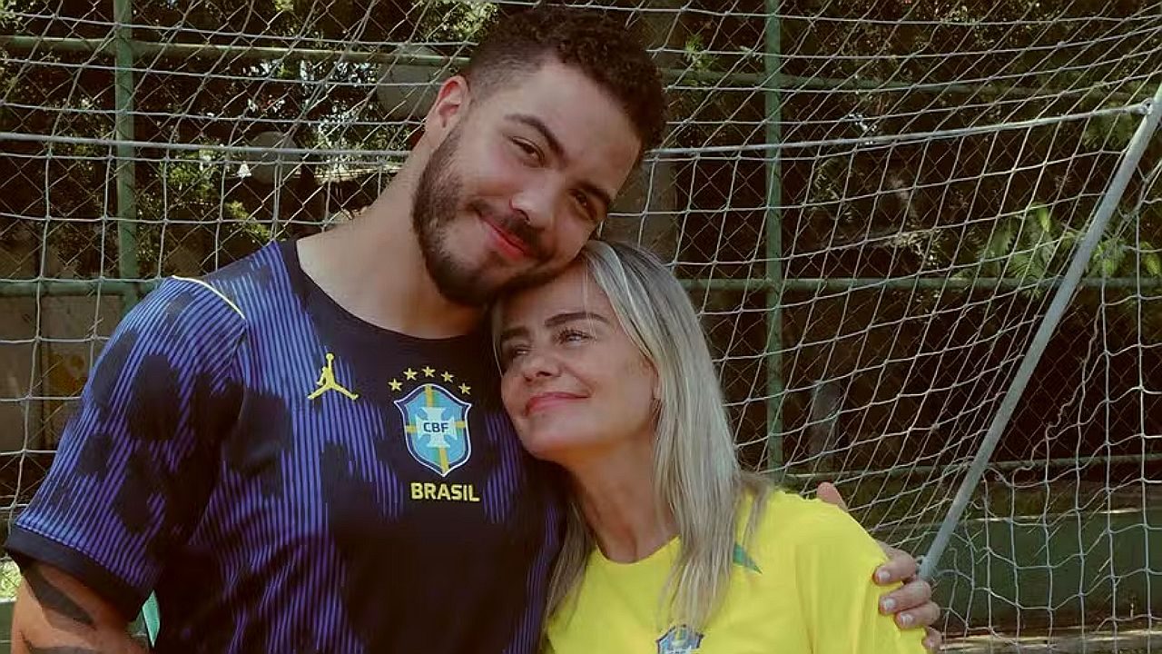 Milene Domingues abraça filho em campo de futebol usando camisas da Seleção Brasileira diante da trave de gol