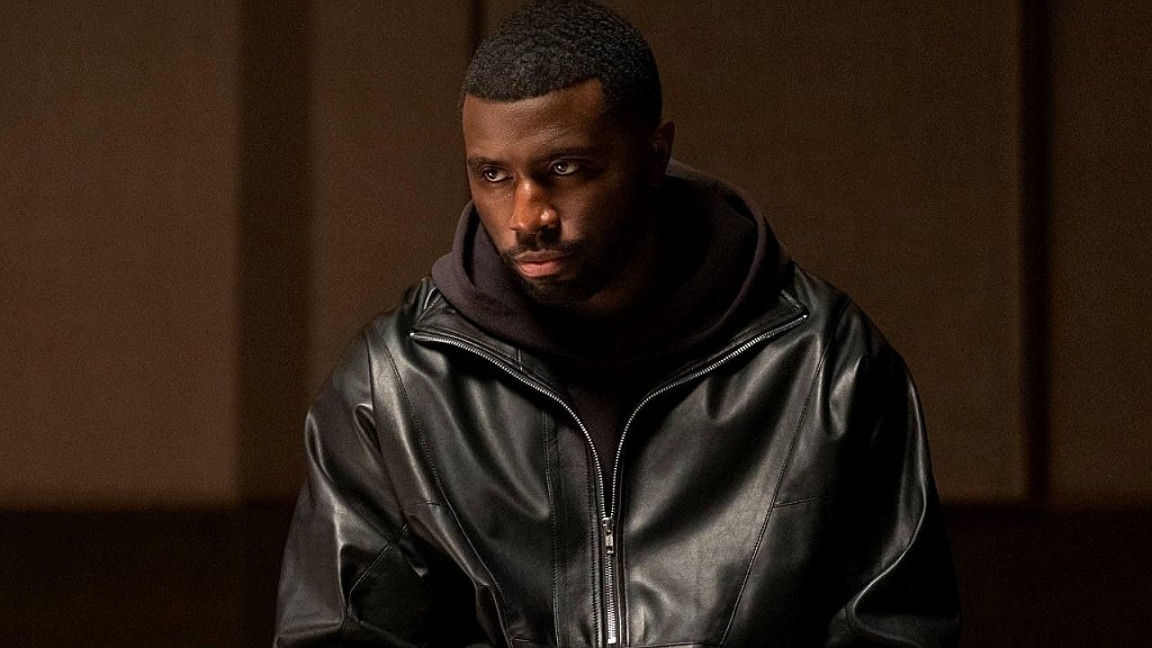 Personagem usa jaqueta de couro preta e encara o horizonte em cena da série Nemesis da Netflix