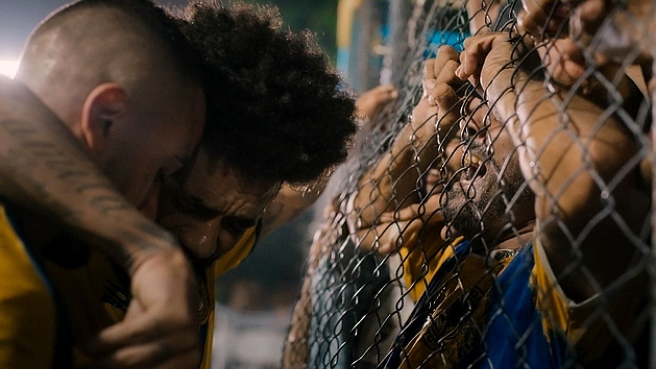 Jogadores e torcedores emocionados junto à grade em cena de série da Netflix sobre futebol brasileiro