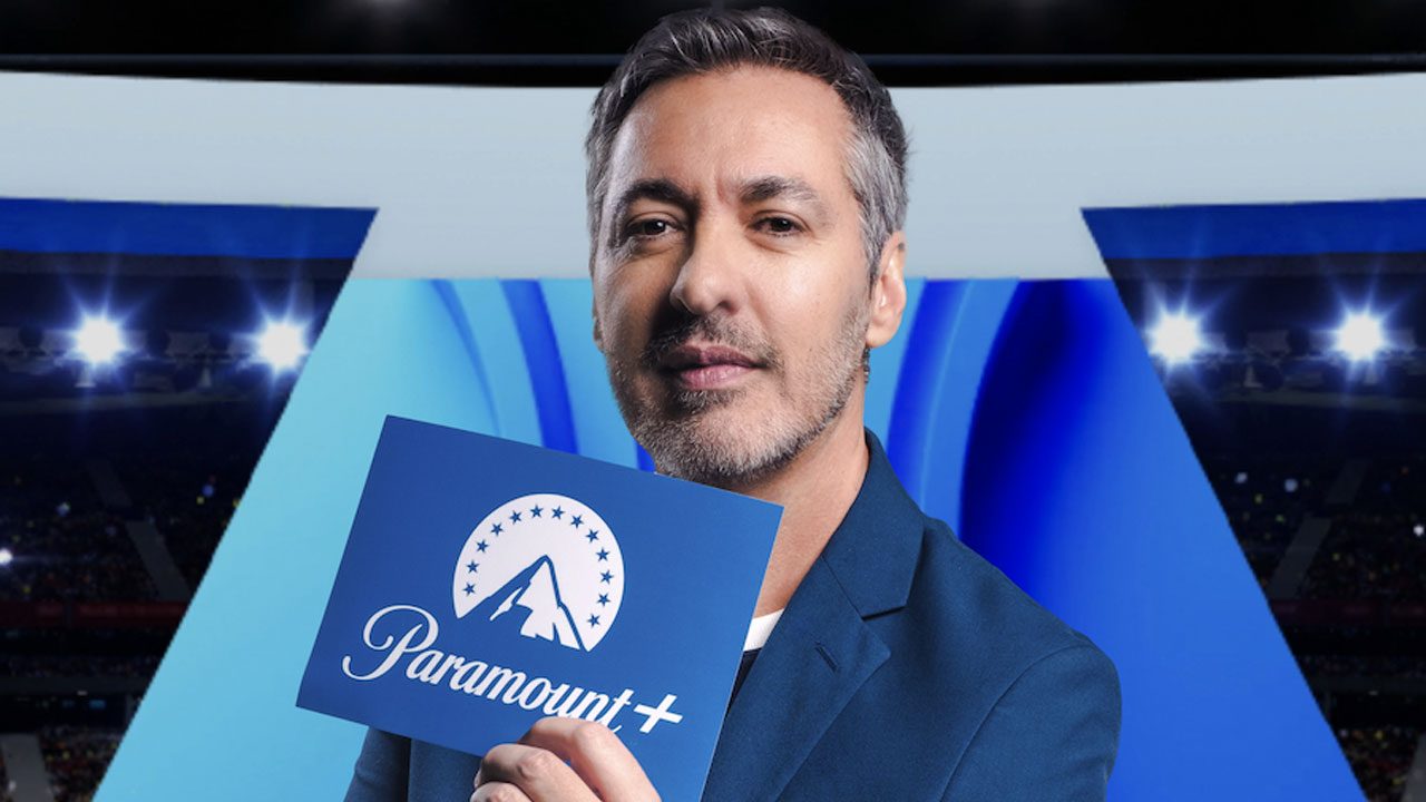Nivaldo Prieto segura placa com logotipo da Paramount+ em estúdio com temática esportiva ao fundo