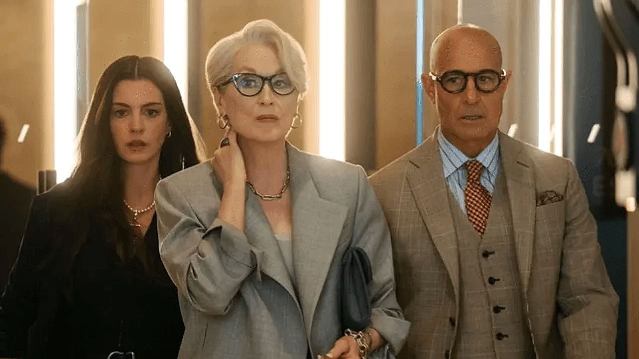 Miranda Priestly acompanhada por Andy e Nigel caminhando em cena de O Diabo Veste Prada em ambiente corporativo