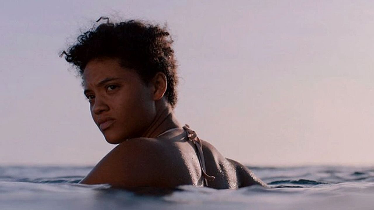 Mulher observa o horizonte enquanto nada no mar em cena dramática ambientada no oceano
